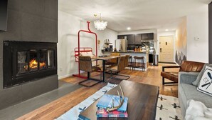 Un salon moderne avec une cheminée, un coin repas et une cuisine en arrière-plan.