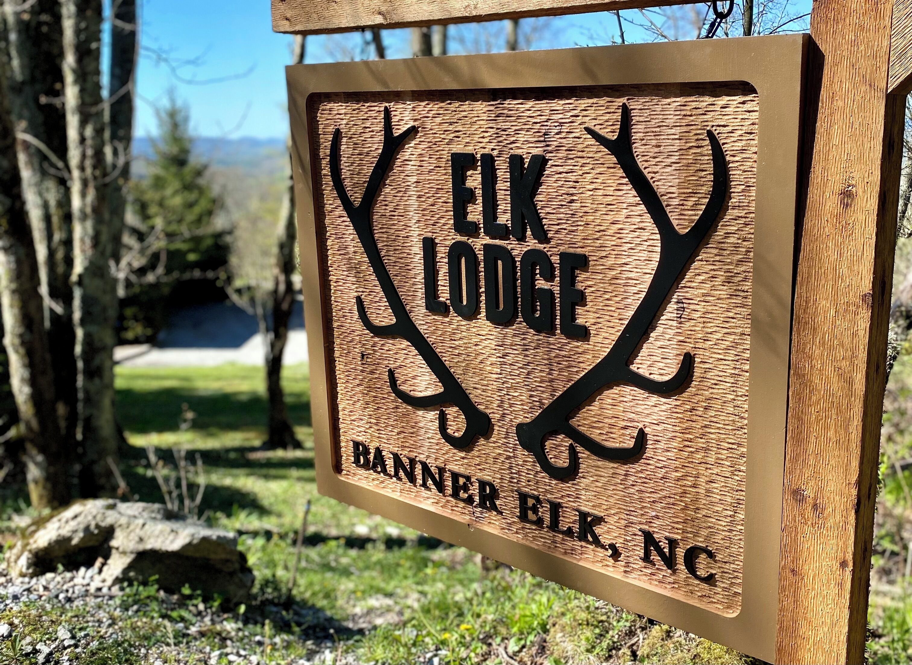 A wooden sign with elk antlers and the text "ELK LODGE BANNER ELK, NC".