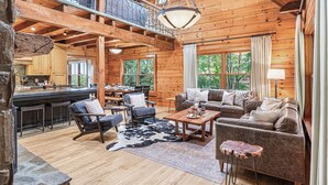 A spacious log cabin with a dining area, a living room with a fireplace, and a kitchen with a large island.