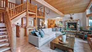 A spacious living area with a wooden staircase, a fireplace, and a cozy seating arrangement. - Riverfront Cabin w/ Hot Tub, Sauna & Fire Pit (Olney)