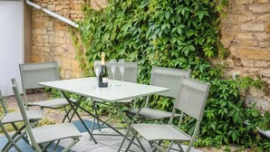 Un espace de restauration en plein air avec une table et des chaises, une bouteille de champagne et des verres.