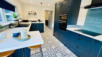 A modern kitchen with dark cabinets, a white countertop, and patterned floor tiles.