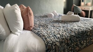 A bedroom with a bed, pillows, a patterned bedspread, and heart-shaped wall decorations. - Sleeps 10 with private garden (Gloucestershire)