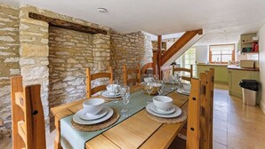 Ein Essbereich mit einem Holztisch, gedeckt für vier Personen, umgeben von Steinmauern und Holzbalken.