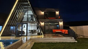 A modern house with a glass facade, a pool, and outdoor seating. - Charming 4-bedroom villa with WiFi and AC in Qəbələ (Qəbələ)
