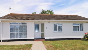 A single-story house with a tiled roof, a front door, and two windows. - Dymchurch Bungalow (Romney Marsh)