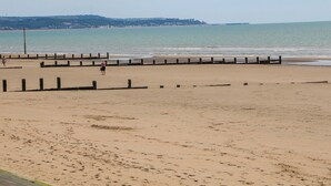 A beach with a wooden jetty and a person walking. - Dymchurch Bungalow (Romney Marsh)