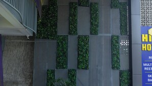 Een moderne hotelentree met een trap, verticale tuinpanelen en een bord.