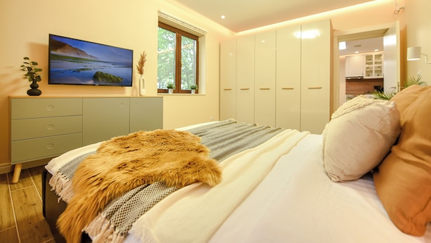 Quarto com cama, televisão, janela e guarda-roupa.