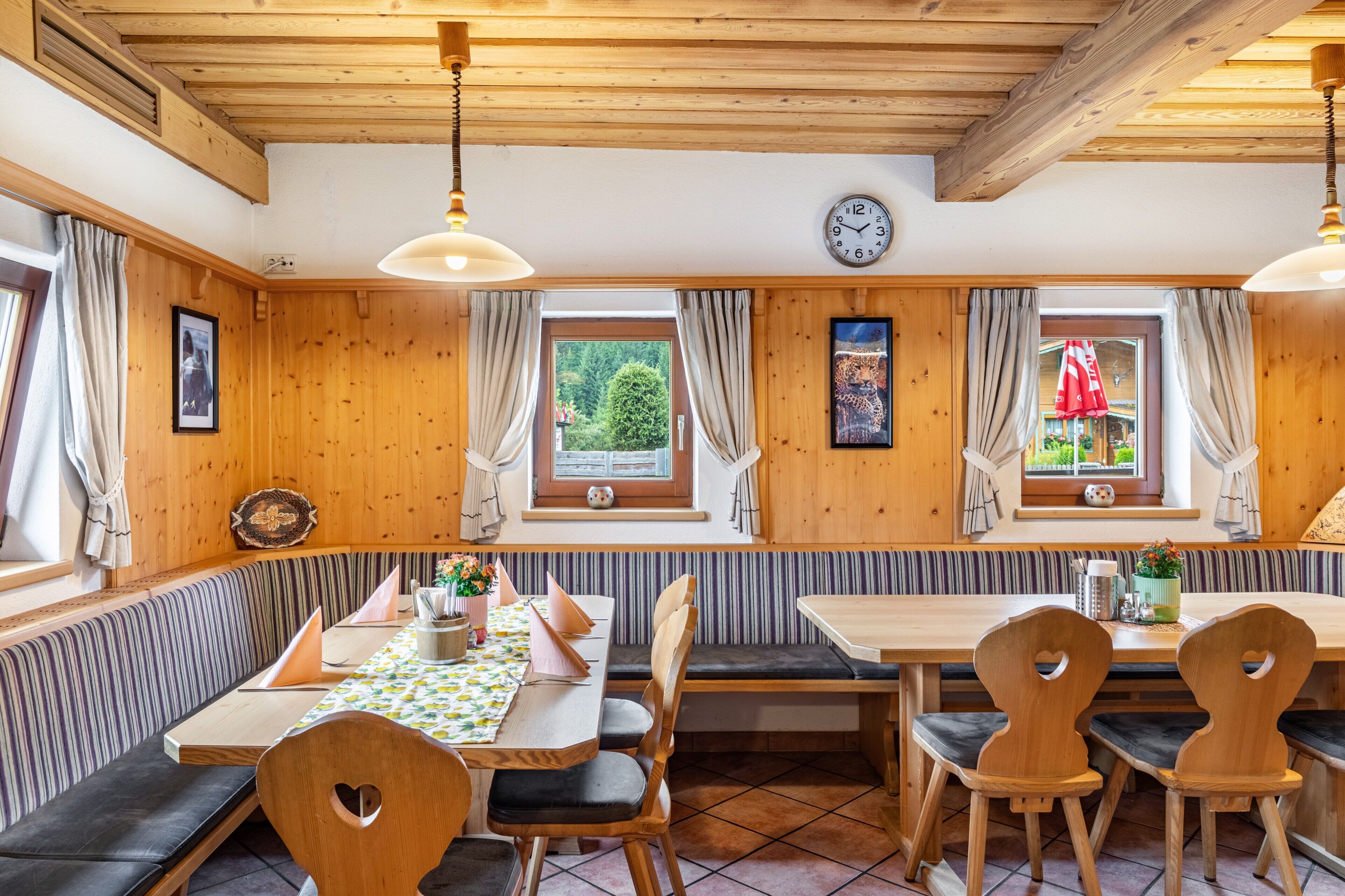 Un intérieur en bois avec une table à manger, des bancs et une horloge au mur.