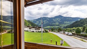 A view from a balcony overlooking a green valley with houses, a flagpole, and a road. - Room '10' with Mountain View, Shared Terrace and Wi-Fi (Hopfgarten in Tirol)