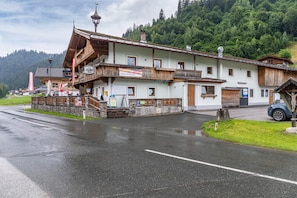 Un bâtiment traditionnel de style alpin, doté d’un balcon, d’une enseigne et d’un mur en pierre.