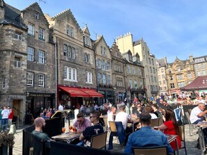 A bustling outdoor café with stone buildings in the background. - Charming Edinburgh Apartment Beside Edinburgh Castle (Edinburgh)