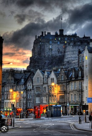 A historic stone building with a prominent tower, situated in a city street with traditional architecture and street lamps. - Charming Edinburgh Apartment Beside Edinburgh Castle (Edinburgh)