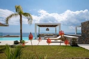 A modern outdoor lounge area with a pool, seating, and a view of the ocean. - Elements Villas (Rhodes)
