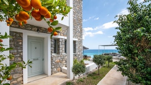 A modern building with a stone facade, a white door, and a view of the sea.
