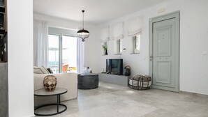 A modern living room with a sofa, a round coffee table, a TV, and a door.