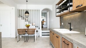 A modern kitchen with a central island, white cabinetry, and a staircase leading to another level.