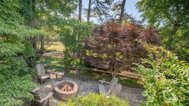 Eine Terrasse mit Feuerstelle, zwei Adirondack-Stühlen und einem kleinen Tisch.