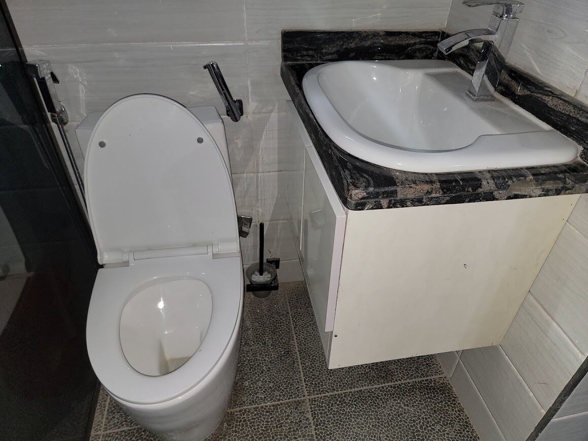 Un baño con inodoro, lavamanos y piso de baldosas.