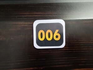 Un panneau noir et blanc portant le numéro 006, fixé sur une surface en bois.