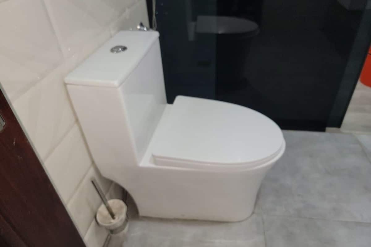 A white toilet in a bathroom with a tiled floor and a glass shower enclosure.