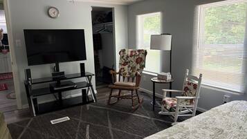 Ein Hotelzimmer mit einem Bett, einem Fernseher, einem Schreibtisch mit Computer, einem Sessel, einer Lampe und einem Schrank.