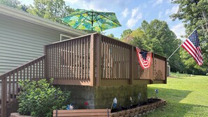 A deck with a wooden railing, a bench, and a flag.