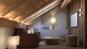 A cozy attic bedroom with a sloped ceiling, wooden beams, a bed, a reading area with a lamp, and a framed picture on the wall.