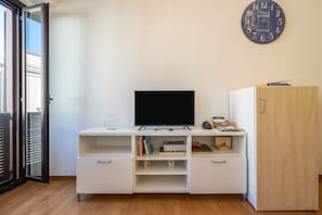 A modern living room with a flat-screen TV, a wooden cabinet, and a wall clock.