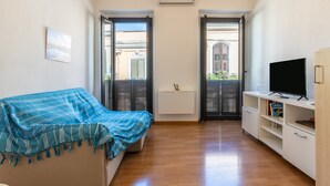 A room with a bed, a TV, a bookshelf, and a radiator.