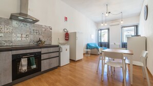 A modern kitchen with a stove, oven, and a small refrigerator. There is a dining area with a table and chairs.