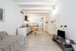 A modern apartment with a kitchen, dining area, and a living room with a sofa and TV.