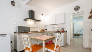 Une cuisine moderne avec des meubles blancs, un four à micro-ondes, un évier et une table à manger avec deux chaises.