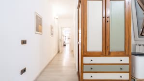 Un couloir avec une armoire en bois, un interrupteur et un tableau encadré accroché au mur.