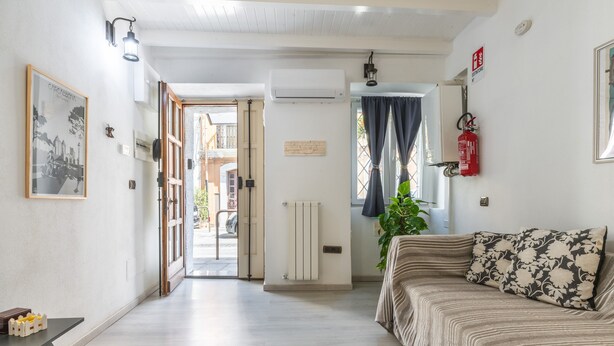 Un salon moderne avec un canapé, un radiateur, un extincteur et un tableau encadré accroché au mur.