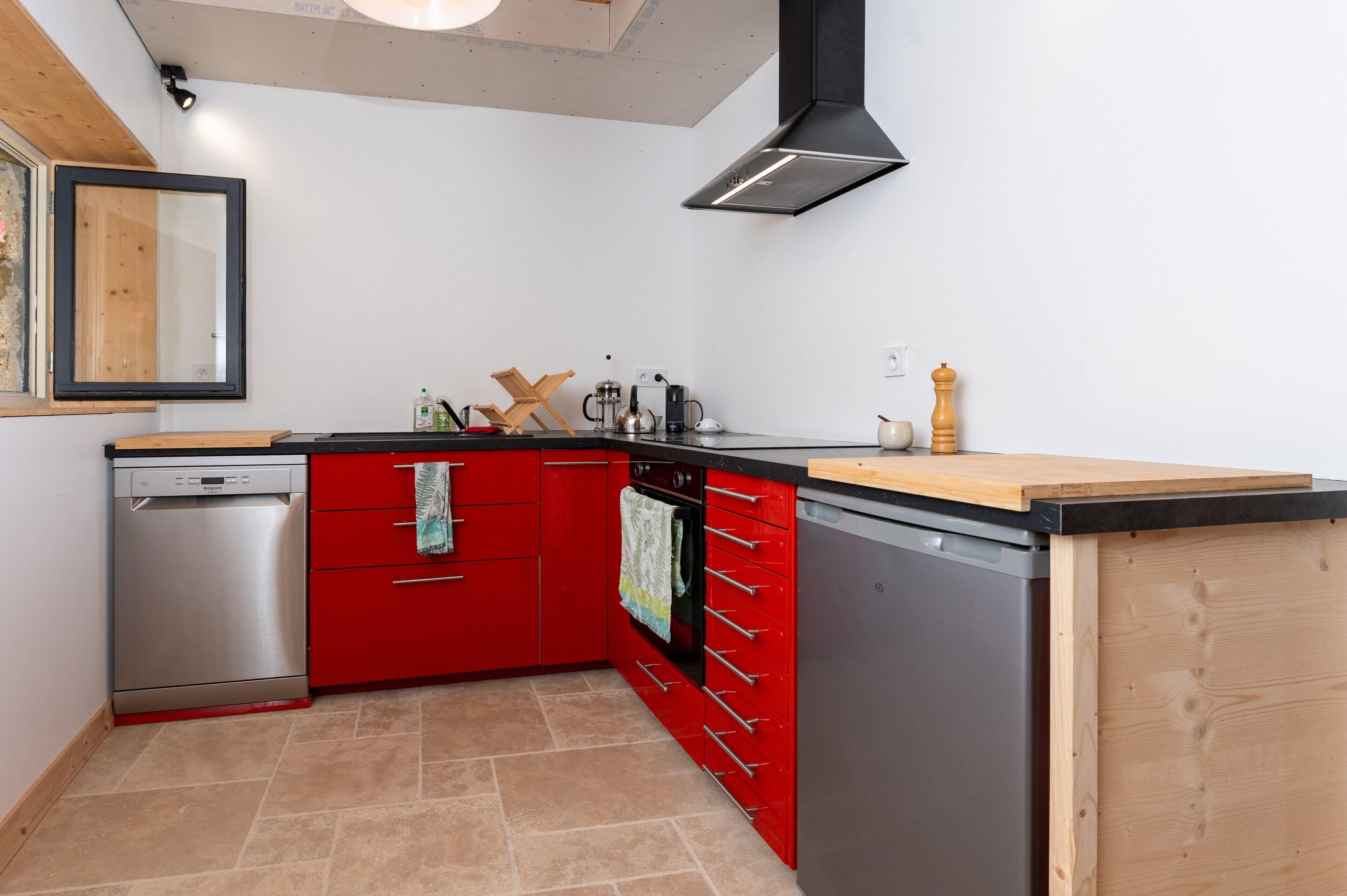 A kitchen with red cabinetry, a dishwasher, an oven, and a wooden countertop.