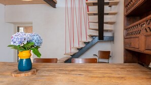 Et spiseområde med et træbord, stole, en vase med blomster, en trappe og et træskab.