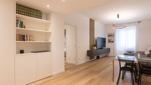 Un salon moderne avec un plancher en bois, une table à manger en verre et une bibliothèque intégrée.