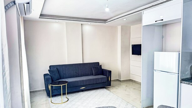 Una sala de estar moderna con un sofá azul oscuro, una mesita redonda y un mueble blanco empotrado.