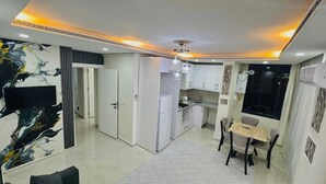 Una cocina moderna con armarios blancos, un comedor con mesa y sillas, y un ventanal grande.