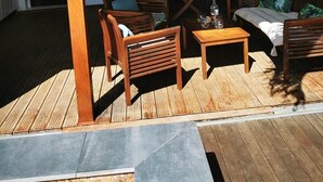 A covered outdoor seating area with wooden furniture, a table, and a ceiling fan. - Following the Horizon of the Balisiers (Sainte-Anne)