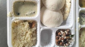 A meal tray with various dishes including two round flatbreads, a lentil dish, a rice dish, and a chickpea dish.