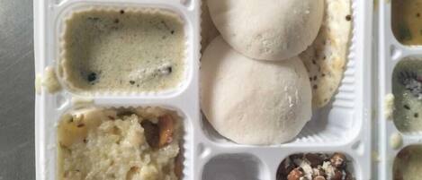 A meal tray with various dishes including two round flatbreads, a lentil dish, a rice dish, and a chickpea dish.