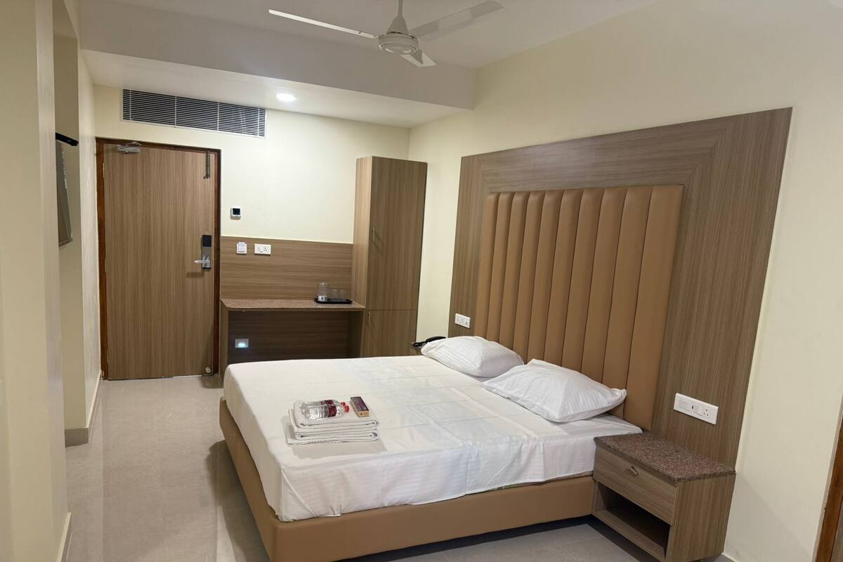 A bedroom with a bed, a wooden headboard, a nightstand, a wardrobe, and a ceiling fan.