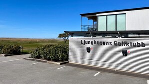 A modern building with a sign reading "Ljunghusens Golfklubb" on the side, featuring a flat roof and a balcony. - 2 Person Holiday Park Home in Testby (Malmö)