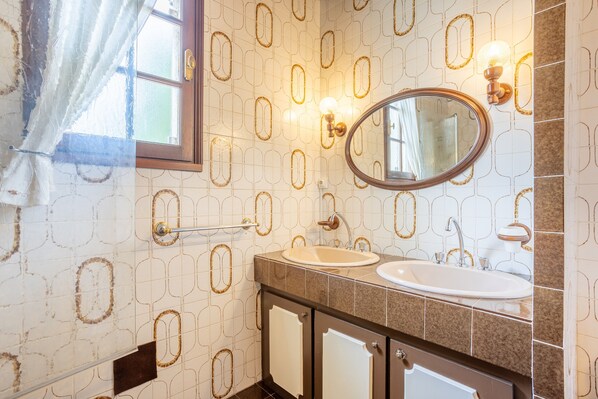 A bathroom with a sink, mirror, towel rack, and patterned wall tiles.