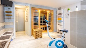 Un baño moderno con ducha, inodoro y una bicicleta estática azul.