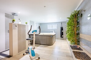 Une salle de bain moderne équipée d’une douche, de toilettes et d’appareils de musculation.