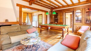 Una sala de estar acogedora con mesa de billar, sofá y estantería.